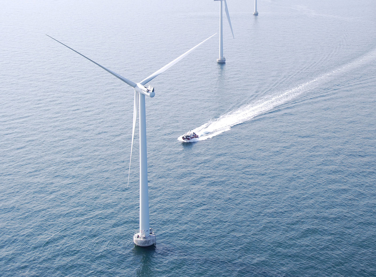 Vessel passing offshore wind turbines on open sea. Vessel passing offshore wind turbines on open sea.